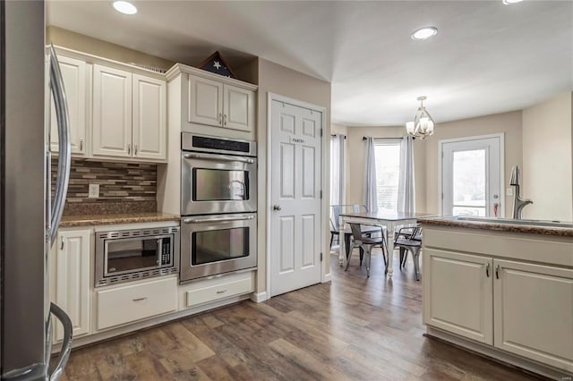 kitchen featuring stainless steel appliances, dark wood-type flooring, a sink, and decorative backsplash