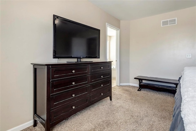 bedroom featuring baseboards, ensuite bath, visible vents, and light colored carpet