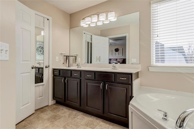 ensuite bathroom featuring double vanity, a sink, ceiling fan, and a bath