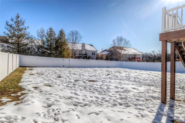 yard layered in snow with a fenced backyard