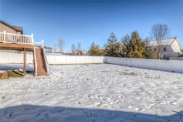 yard layered in snow featuring a fenced backyard, stairway, and a wooden deck