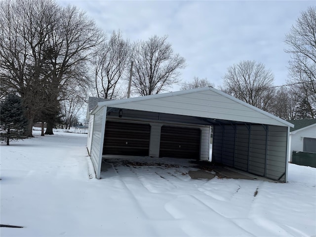 snow covered garage featuring a carport