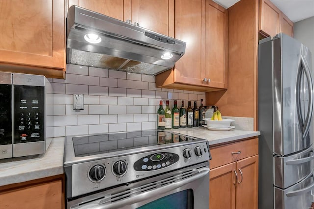 kitchen featuring stainless steel appliances, light stone counters, and decorative backsplash