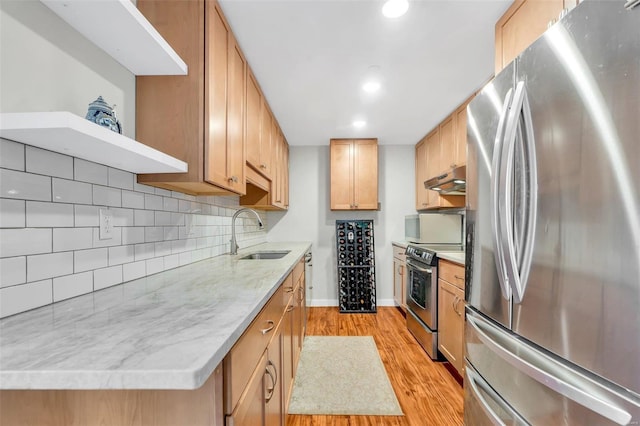 kitchen with light stone countertops, stainless steel appliances, light hardwood / wood-style floors, sink, and backsplash