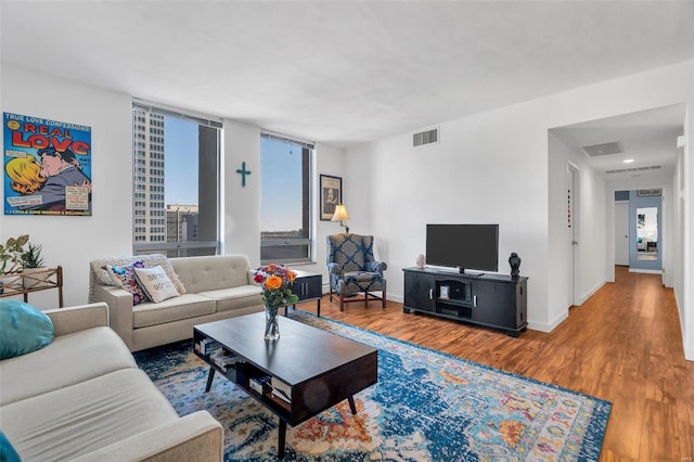 living area featuring visible vents, baseboards, and wood finished floors