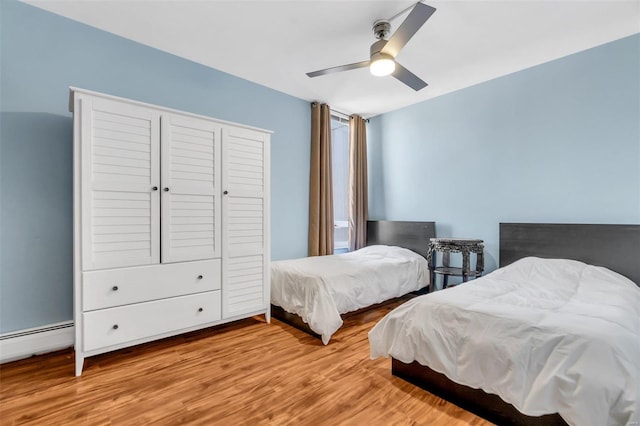 bedroom featuring ceiling fan, a baseboard heating unit, and wood finished floors