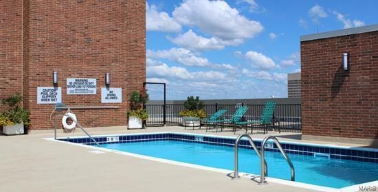 pool with a patio area and fence