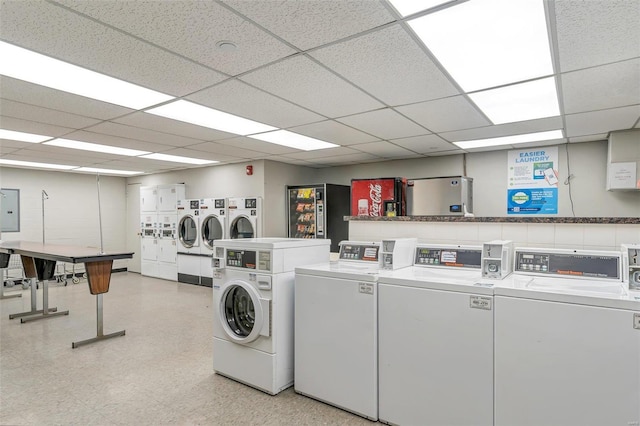 shared laundry area with electric panel, washing machine and dryer, and light floors