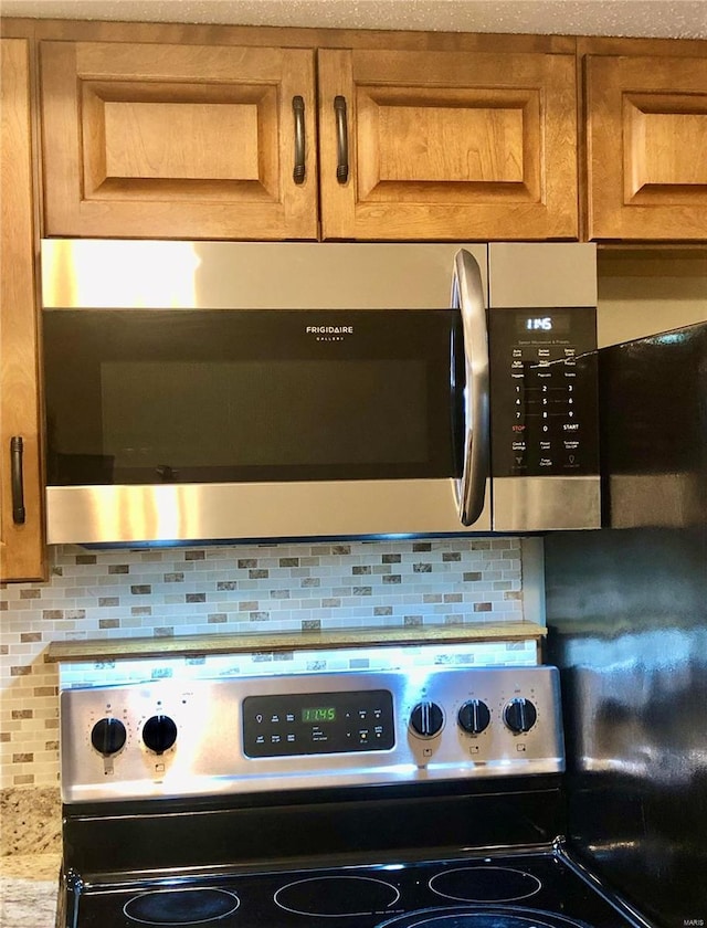 details with stainless steel appliances, decorative backsplash, and light stone countertops