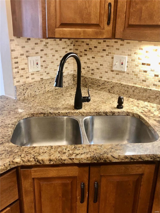 interior details featuring light stone countertops, sink, and tasteful backsplash