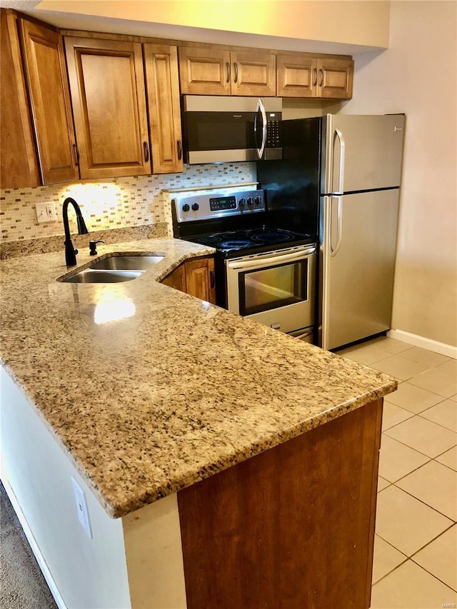 kitchen featuring light tile patterned floors, light stone countertops, stainless steel appliances, and sink