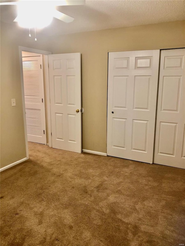 unfurnished bedroom with a textured ceiling, ceiling fan, and carpet flooring