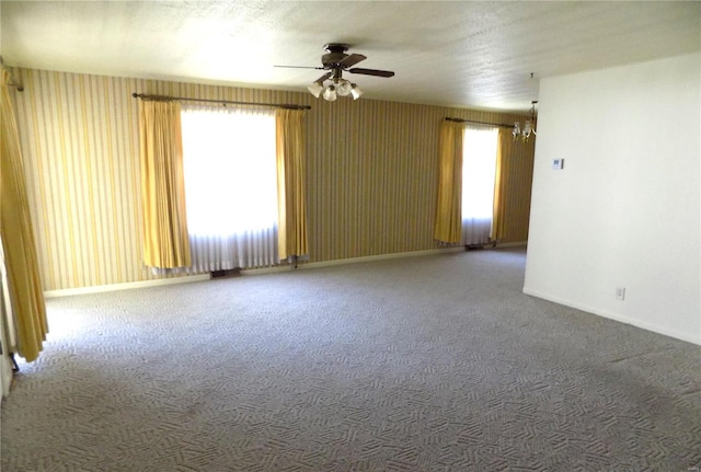 carpeted empty room with ceiling fan with notable chandelier