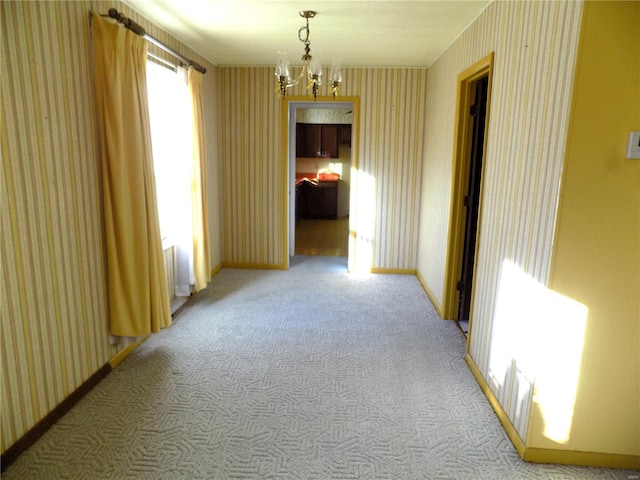 empty room featuring light carpet and a notable chandelier