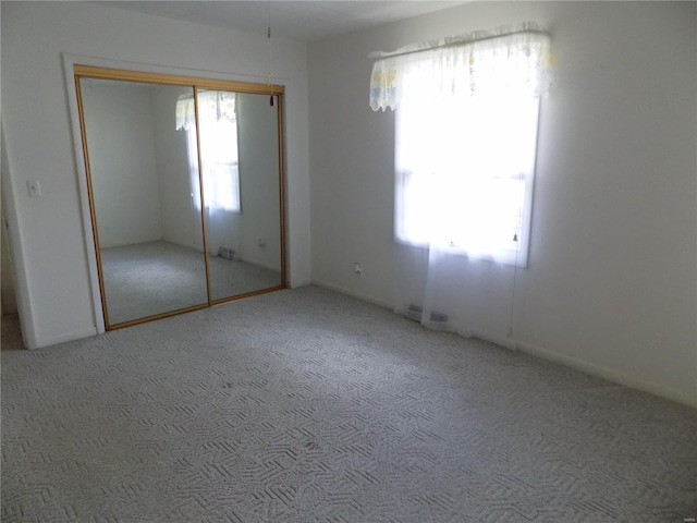 unfurnished bedroom featuring a closet, multiple windows, and carpet