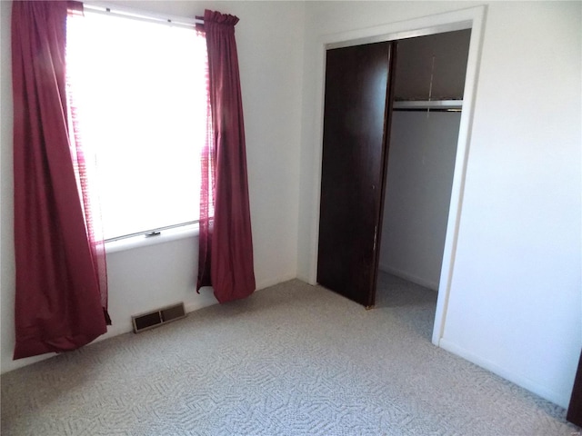 unfurnished bedroom featuring light colored carpet and a closet