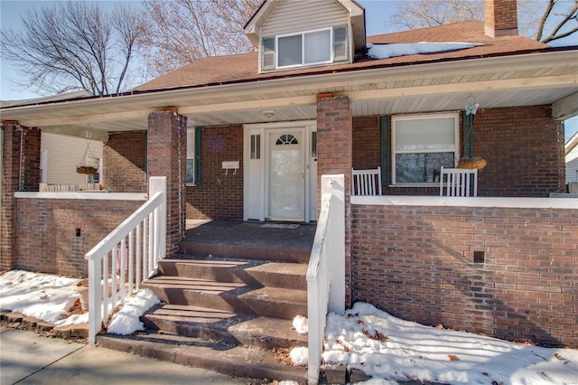 snow covered property entrance featuring a porch