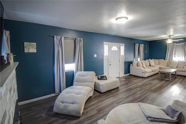 living room with ceiling fan, dark hardwood / wood-style flooring, and a textured ceiling