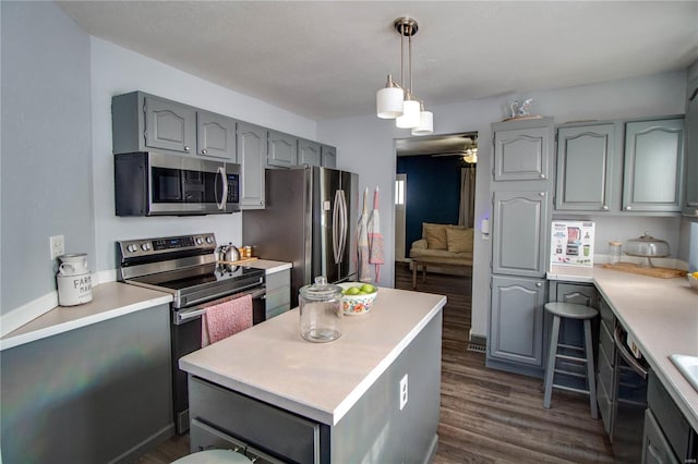 kitchen featuring decorative light fixtures, ceiling fan, dark hardwood / wood-style floors, a center island, and appliances with stainless steel finishes