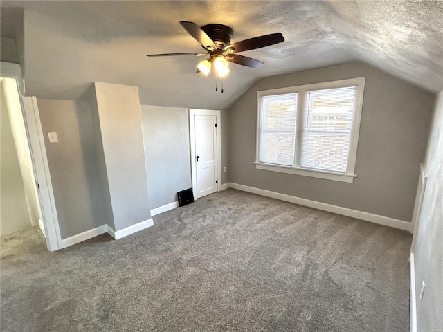 unfurnished bedroom featuring ceiling fan, a textured ceiling, carpet floors, and lofted ceiling