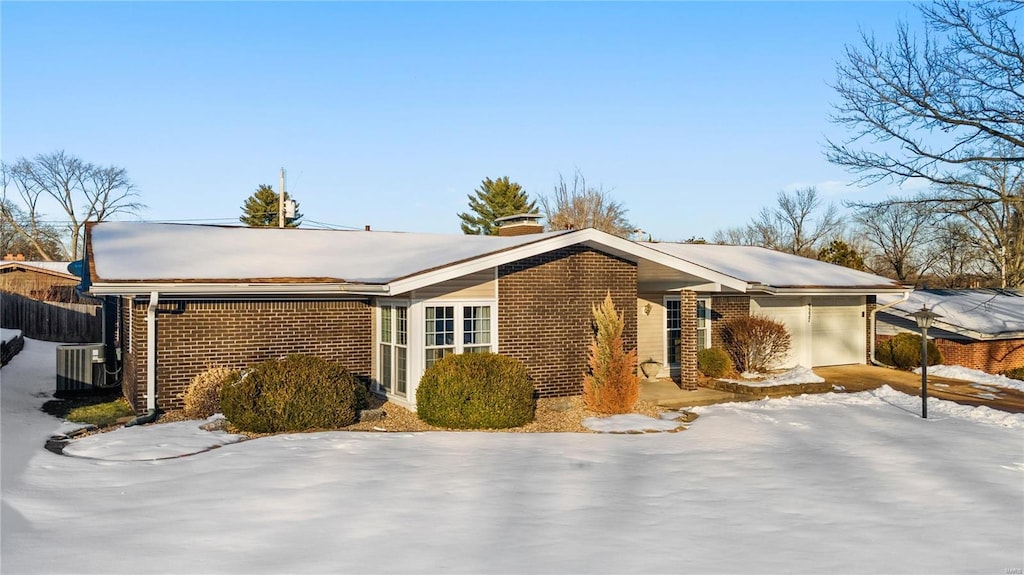 view of snow covered exterior with a garage and central air condition unit