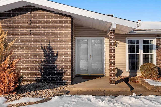 snow covered property entrance with french doors and a patio