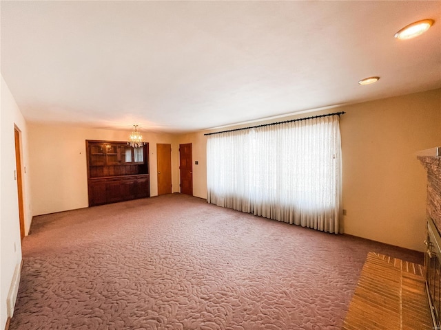 unfurnished living room featuring a notable chandelier and carpet floors