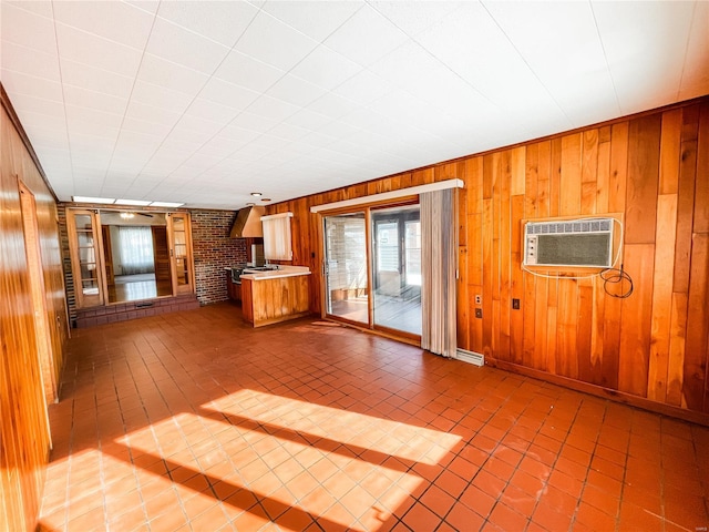 unfurnished living room featuring tile patterned flooring, a wall mounted air conditioner, and wood walls