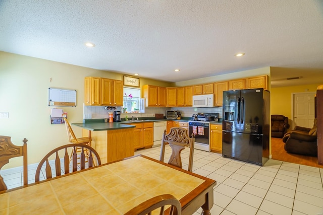 kitchen featuring kitchen peninsula, decorative backsplash, white appliances, light tile patterned flooring, and a textured ceiling