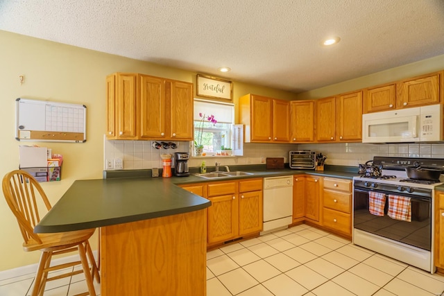 kitchen featuring light tile patterned flooring, sink, kitchen peninsula, and white appliances