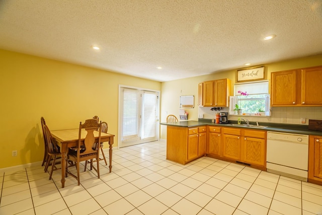 kitchen with light tile patterned floors, dishwasher, sink, and a textured ceiling