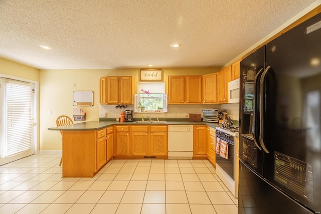 kitchen with kitchen peninsula, sink, white appliances, and a textured ceiling