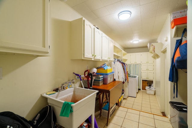 kitchen featuring light tile patterned floors, white cabinets, sink, and washing machine and clothes dryer