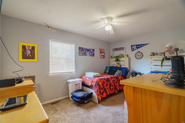 bedroom with ceiling fan, carpet floors, and a textured ceiling