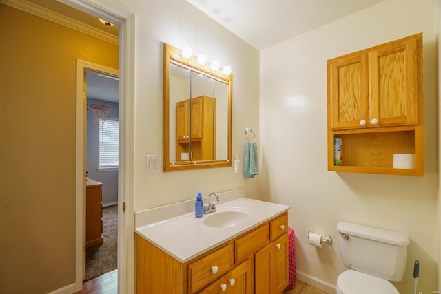 bathroom with toilet, vanity, and crown molding