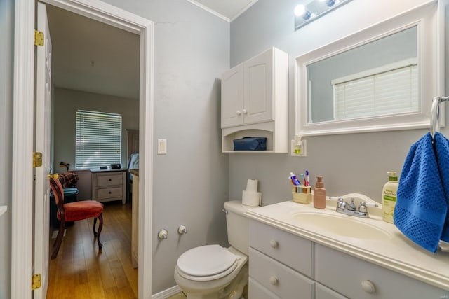 bathroom with wood-type flooring, toilet, vanity, and crown molding