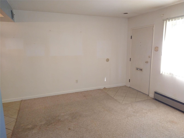 spare room featuring light tile patterned floors, baseboards, baseboard heating, and light colored carpet