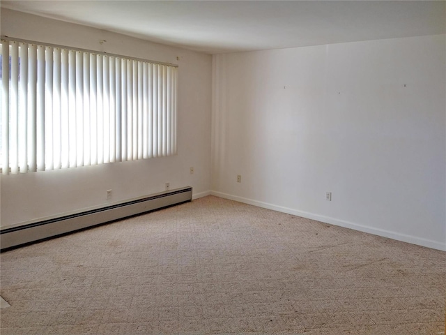 spare room with carpet floors, baseboards, and a baseboard heating unit