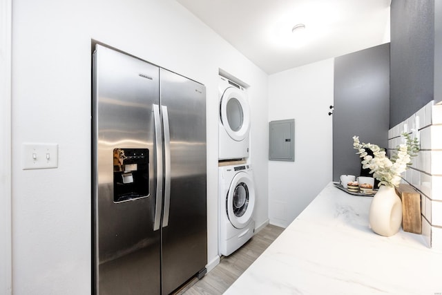 washroom featuring stacked washer and clothes dryer, electric panel, and light hardwood / wood-style floors