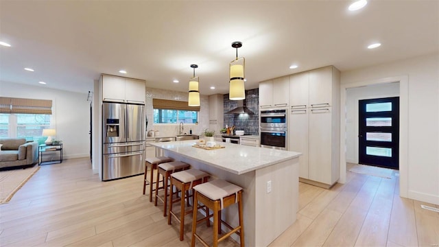 kitchen with hanging light fixtures, stainless steel appliances, white cabinets, and a kitchen island