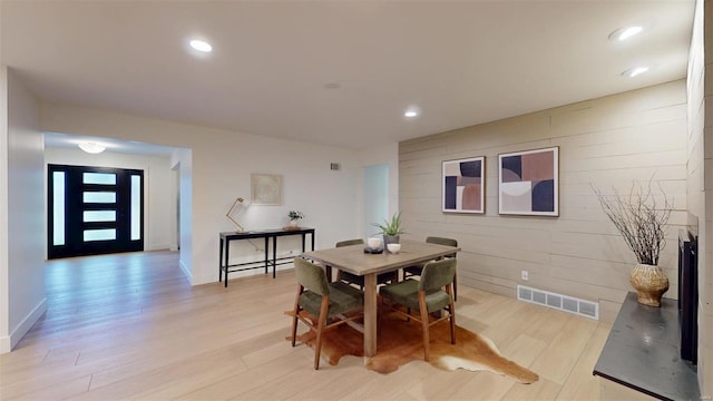 dining area featuring wooden walls and light wood-type flooring