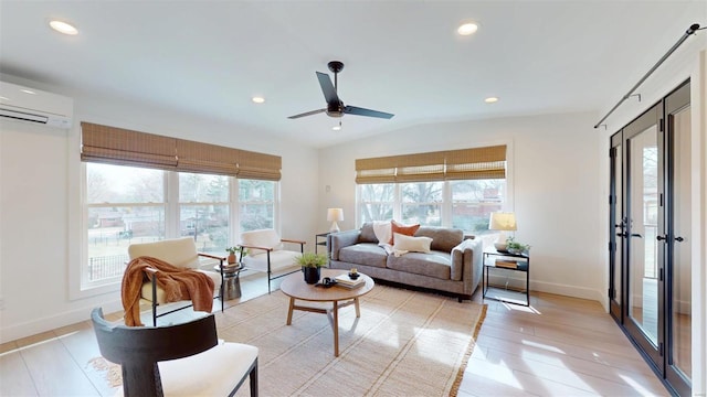 living room featuring ceiling fan, lofted ceiling, light wood-type flooring, and a wall unit AC