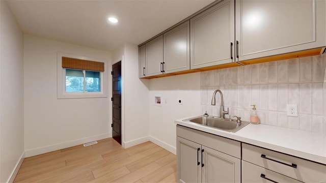 kitchen featuring gray cabinetry, sink, backsplash, and light hardwood / wood-style floors