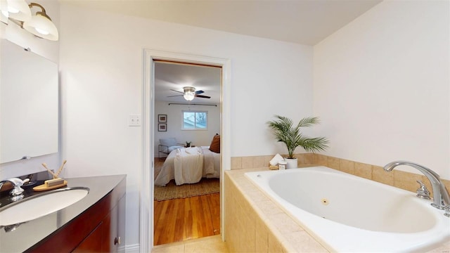 bathroom featuring hardwood / wood-style flooring, vanity, and tiled tub