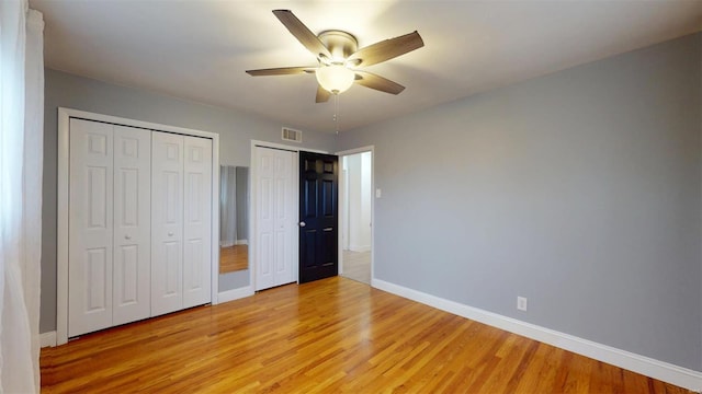 unfurnished bedroom featuring multiple closets, ceiling fan, and light wood-type flooring