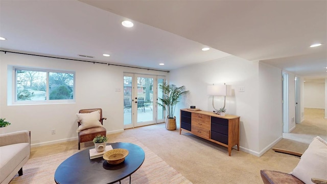 living area featuring french doors, plenty of natural light, and light carpet