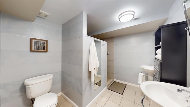 bathroom featuring sink, tile patterned flooring, tile walls, toilet, and walk in shower