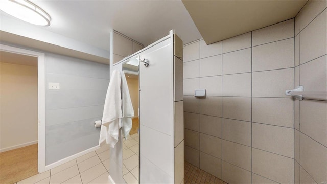 bathroom with a tile shower and tile patterned floors