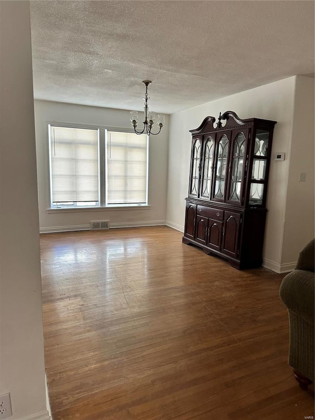 unfurnished dining area with wood-type flooring and a notable chandelier