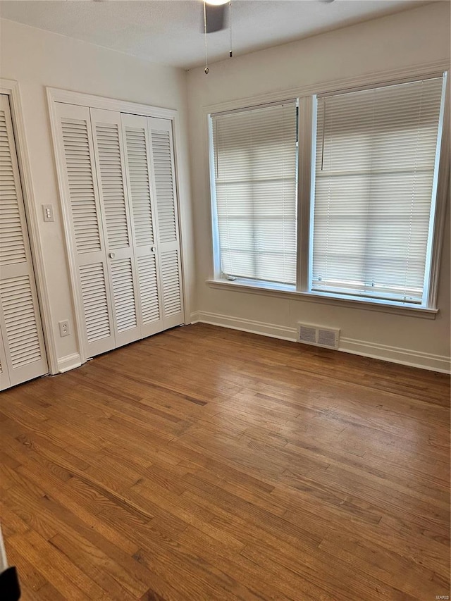 unfurnished bedroom featuring wood-type flooring and multiple closets